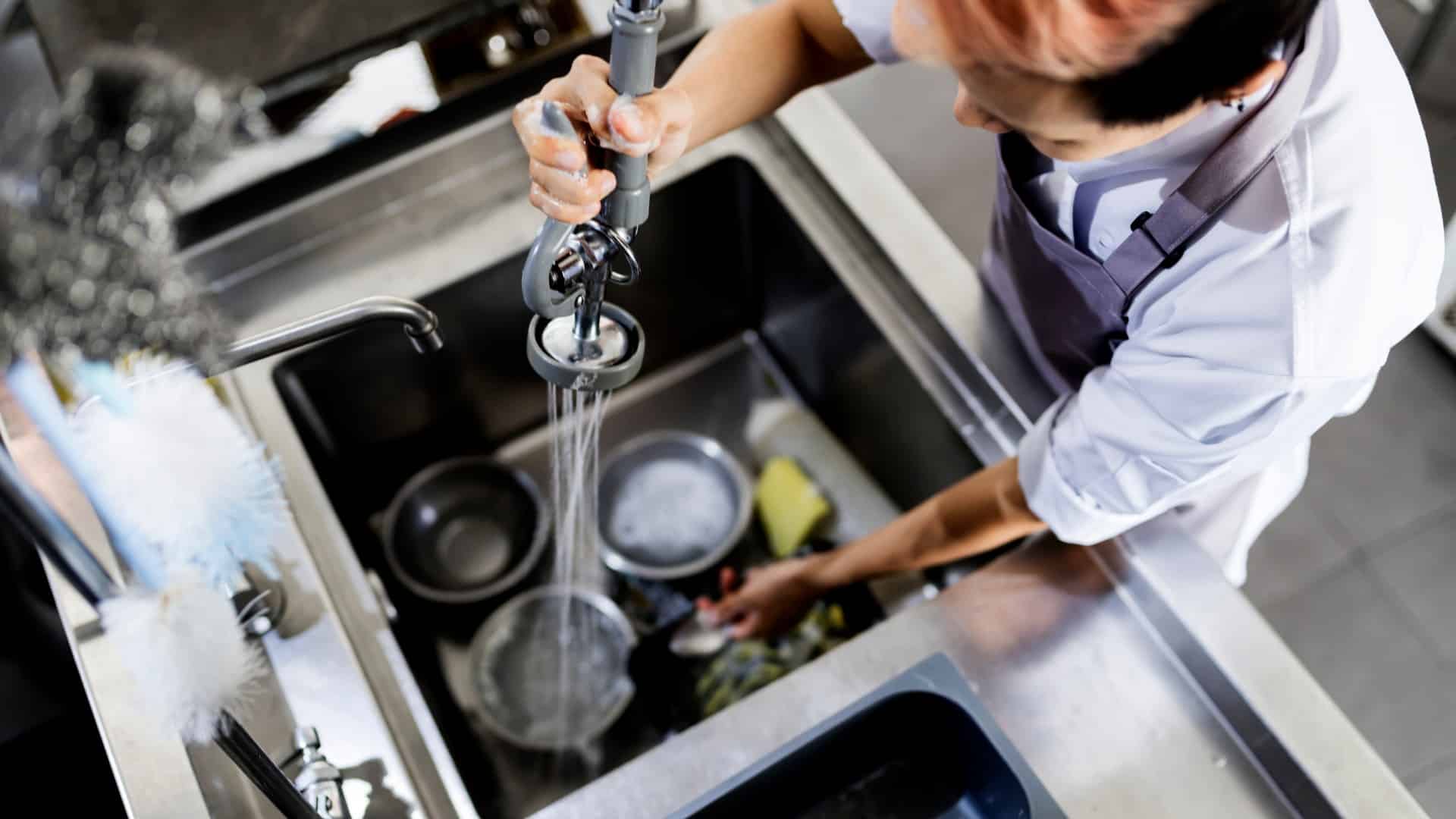 Top view of kitchen staff washing utensils at sink